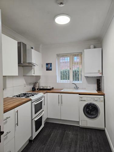 a kitchen with white cabinets and a washer and dryer at Harry Potter Hogwarts apartment in Leavesden Green