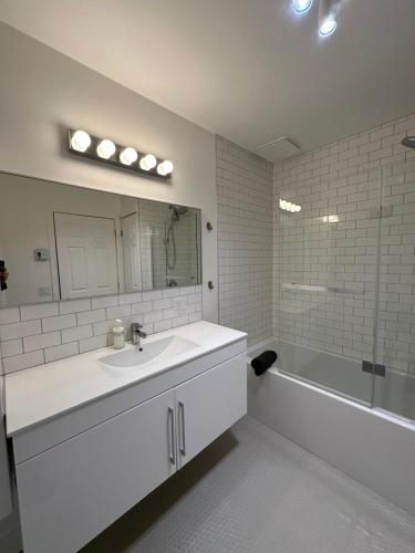 a white bathroom with a sink and a bath tub at Le 315B Limoilou "parking inclus" in Quebec City