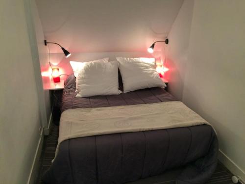 Cette petite chambre comprend un lit avec deux oreillers et deux lumières. dans l'établissement Appartement charmant à Hautot-sur-Mer, 45 m² avec stationnement, à Hautot-sur-Mer