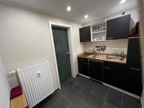a kitchen with black cabinets and a sink at Boarding House "Alte Schusterei" am Ahnepark in Vellmar