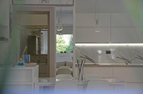 a kitchen with white cabinets and white chairs in it at Appartamento Emozione Mare Blu San Terenzo in Lerici