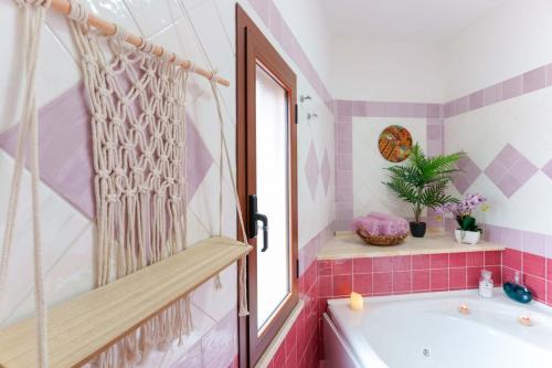 une salle de bains rose avec une baignoire et une fenêtre dans l'établissement Villa Wunjo IUN R3267, à La Maddalena
