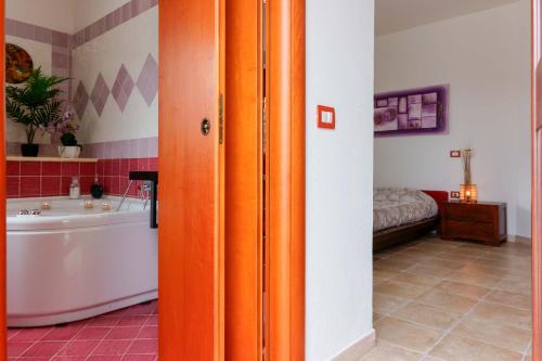 - une porte orange dans une salle de bains avec baignoire et une chambre dans l'établissement Villa Wunjo IUN R3267, à La Maddalena