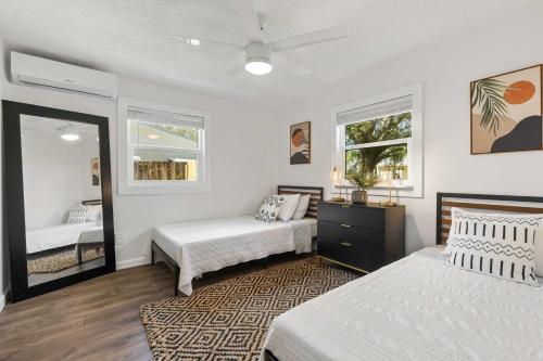 a bedroom with two beds and a mirror at 4 Mi to Dtwn Jensen Beach Cottage in Jensen Beach