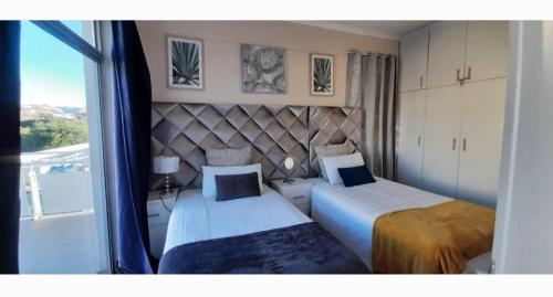 een slaapkamer met 2 bedden en een groot raam bij Maerua Mall Luxe Accommodations 3rd Floor in Windhoek
