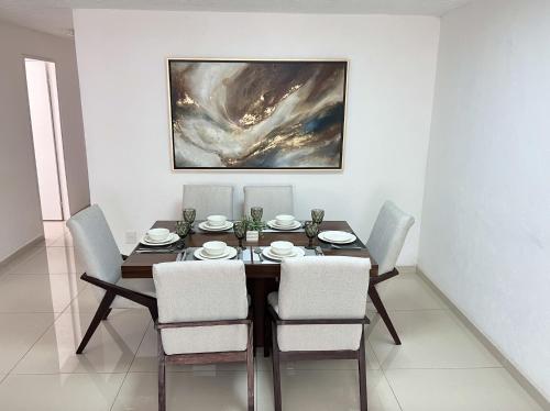 a dining room table with chairs and a painting on the wall at Suites Jacarandas 203 in Guadalajara