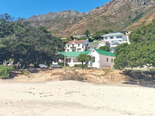 a group of houses on a beach with a mountain at Milkwood Cottage, Beachfront family vacation home, Sleeps 6 in Gordonʼs Bay