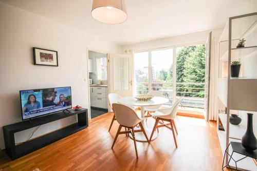 een woonkamer met een tafel en stoelen en een televisie bij Apartment with balcony, parking and elevator in Lille