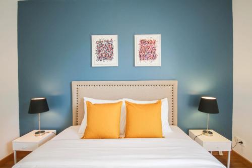 een slaapkamer met een blauwe muur en een bed met oranje kussens bij Apartment with balcony, parking and elevator in Lille