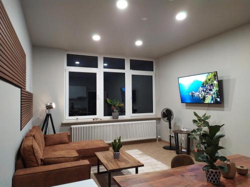 a living room with a couch and a tv on a wall at Andris Apartments in Stuttgart