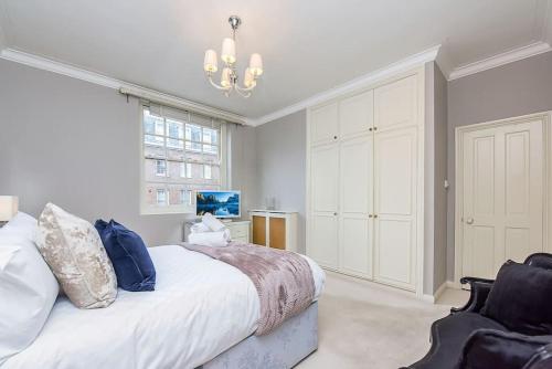 een slaapkamer met een groot bed en een kroonluchter bij 2 Bedroom Apartment- Mayfair (4) in Londen