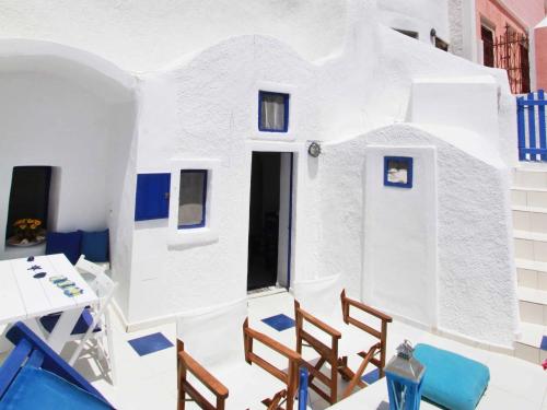 Habitación con una casa blanca con sillas y mesa en Blu Bianco Cave House by SV, en Oia
