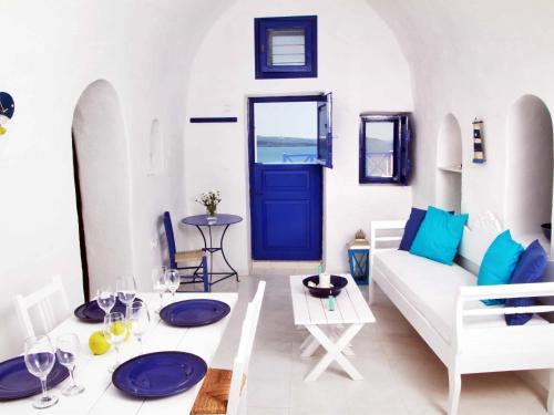 sala de estar con sofá blanco y puerta azul en Blu Bianco Cave House by SV, en Oia