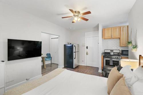a bedroom with a bed with a ceiling fan and a kitchen at Trendy Studio Apartment in Chicago - Kenwood 103 & 303 rep in Chicago