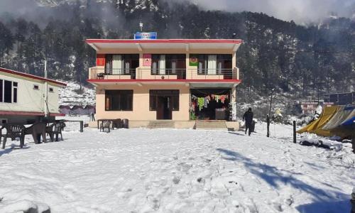 a man standing in front of a building in the snow at Hotel The River wood in Kasol