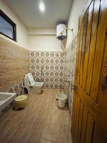 a bathroom with a toilet and a sink and a door at Hotel The River wood in Kasol