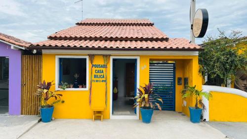a small yellow house with a red roof at Pousada Bilica in Arraial d'Ajuda
