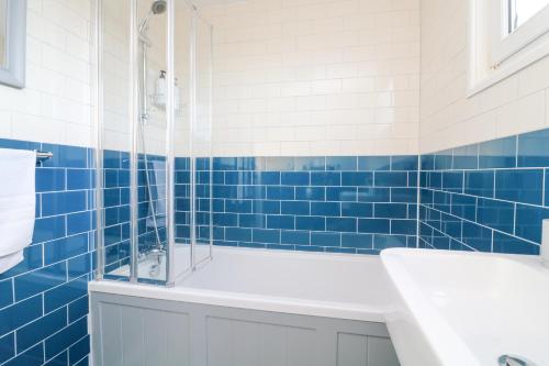 8 Little Hill في سالكومب: حمام من البلاط الأزرق مع حوض استحمام ومغسلة