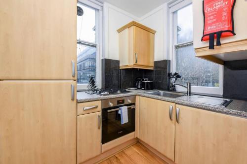a kitchen with wooden cabinets and a refrigerator at Central London- 1 Bed Apartment! in London