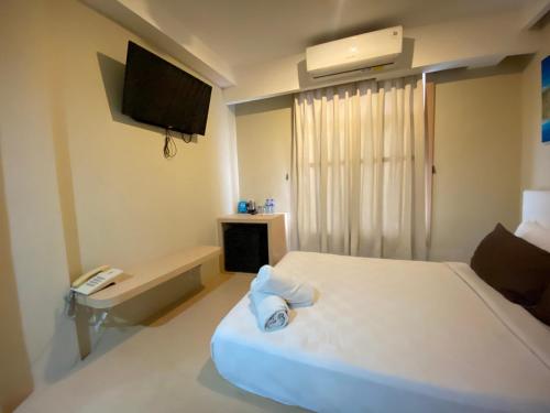 a room with a bed with a phone and a television at Kimono Spa Hotel in Kuta