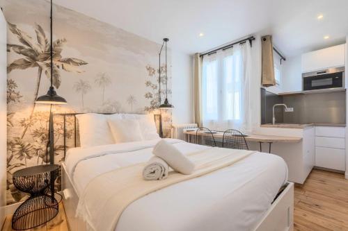 une chambre avec un grand lit blanc et une cuisine dans l'établissement Hypercentre Beaux-Arts charming studio Lille, à Lille