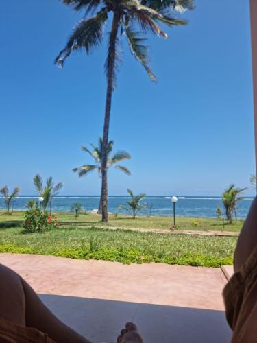 une personne assise sur une terrasse couverte donnant sur la plage dans l'établissement Villa 5 Casa Di Kasa, à Kilifi