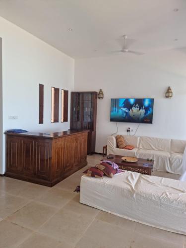 sala de estar con 2 sofás blancos y TV en Villa 5 Casa Di Kasa, en Kilifi