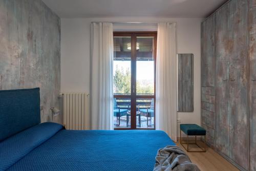 a bedroom with a blue bed and a window at Maison Alice in Soiano del Lago