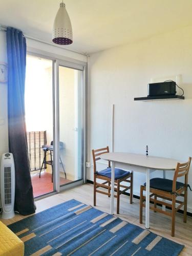 un salon avec une table et des chaises et un balcon dans l'établissement Agréable studio 50m de la plage, à Canet