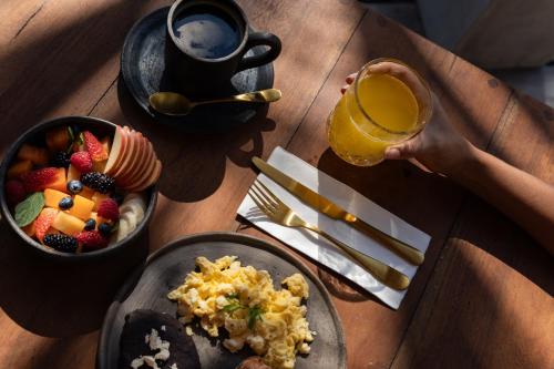 a person holding a glass of orange juice and a plate of breakfast food at UMi Tulum in Tulum