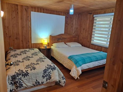 2 camas num quarto com paredes e pisos em madeira em HOSTAL CARHUELLO em Pucón