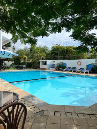 a large blue swimming pool with chairs and trees at Waves and Wanderlust- Nyali Sunrise in Nyali