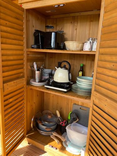 a wooden cabinet with dishes and utensils in it at Bubble Tent Berlin in Altlandsberg