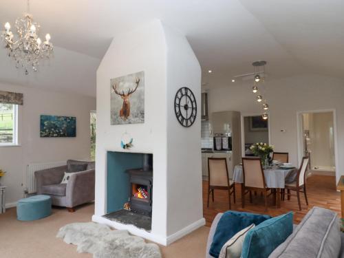 a living room with a fireplace and a dining room at Hazelnut Lodge in Crediton