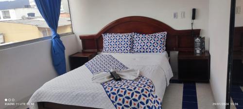 a bedroom with a bed with blue and white pillows at HOTEL EL PARAISO in Bogotá
