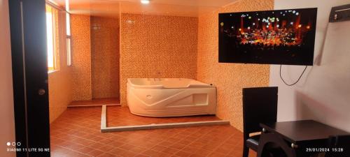 a bathroom with a urinal and a tv on the wall at HOTEL EL PARAISO in Bogotá