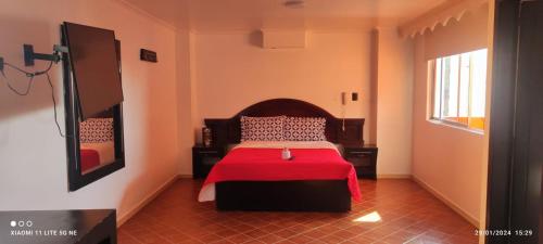 a bedroom with a bed with a red blanket at HOTEL EL PARAISO in Bogotá