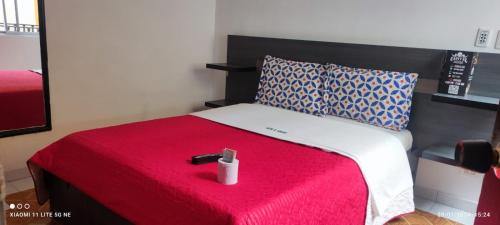 a bed with a red blanket and a candle on it at HOTEL EL PARAISO in Bogotá