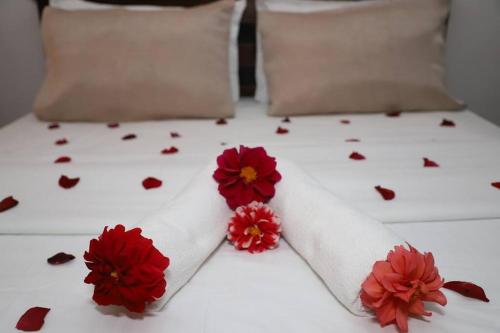 een wit bed met rode bloemen erop bij Dawn's Bungalow in Nuwara Eliya