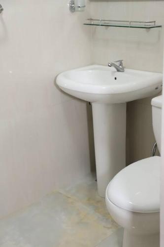 a white bathroom with a sink and a toilet at Dawn's Bungalow in Nuwara Eliya