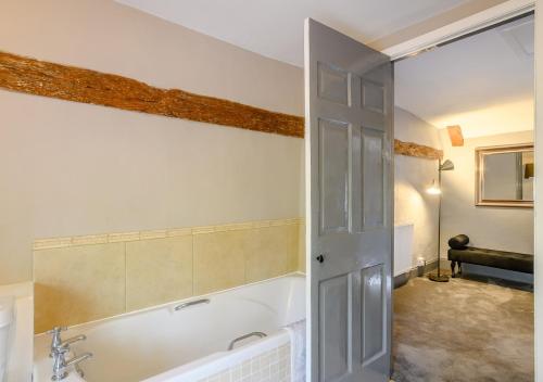 a bathroom with a bath tub and a sink at Grove Cottage in Horstead