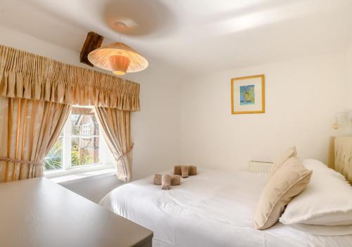 a bedroom with a white bed and a window at Grove Cottage in Horstead