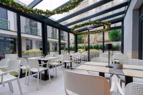 a restaurant with white chairs and tables and windows at Onyx Luxury Budapest in Budapest