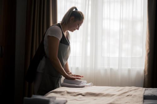 a woman putting towels on top of a bed at Šport Hotel *** Donovaly in Donovaly