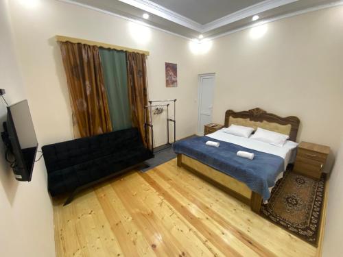 a bedroom with a bed and a couch and a television at Guesthouse LUKA in Kutaisi