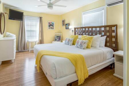 um quarto com uma grande cama branca com almofadas amarelas em Road's End by Brightwild em Key West