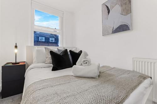 Cama blanca con almohadas negras y ventana en 1 Bed- Hyde Park- Central London, en Londres