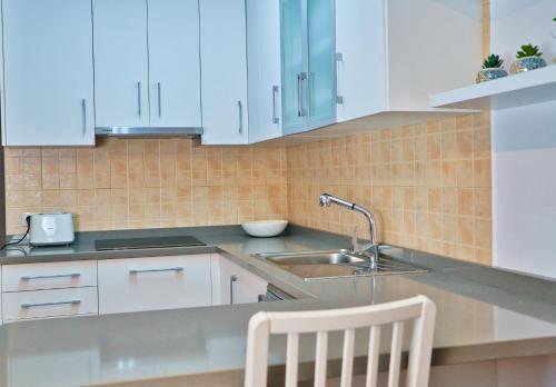 a kitchen with white cabinets and a sink at VolcanoKite Brisa Home in Famara