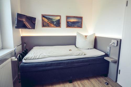 a small bed in a room with a tv at Hotel Kalenborner Höhe in Kalenborn