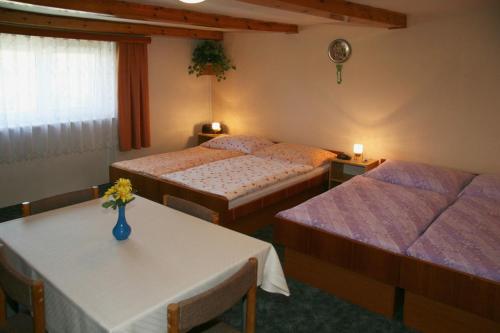 a bedroom with two beds and a table with a vase on it at Chalupa Nemilkov in Velhartice